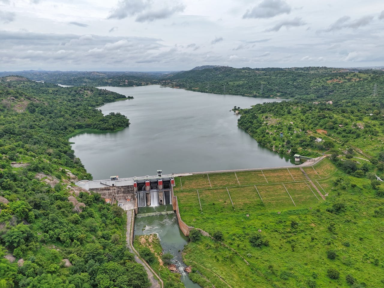 Aerial shot of lush green landscape with a dam and reservoir in Bengaluru, India.